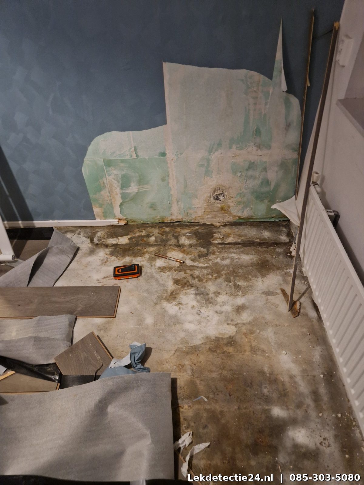 Waterschade aan muur, vloer en plinten door leidinglek